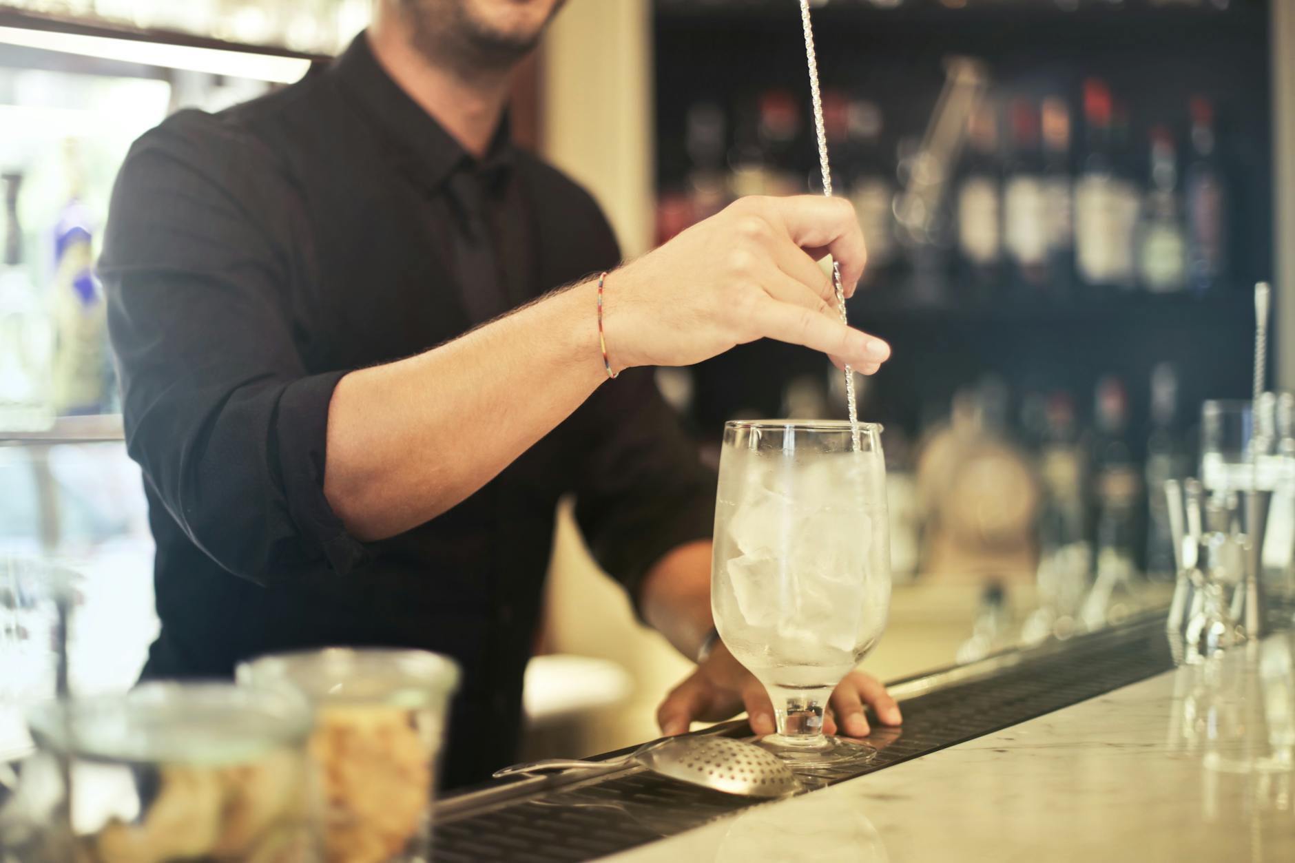 Crop barman making cocktail in pub