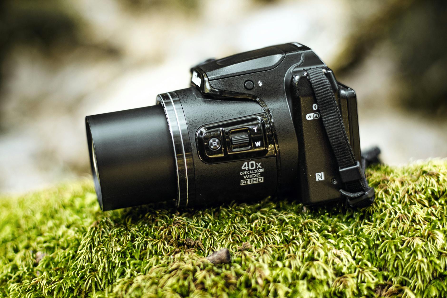 A digital camera sitting on top of some moss