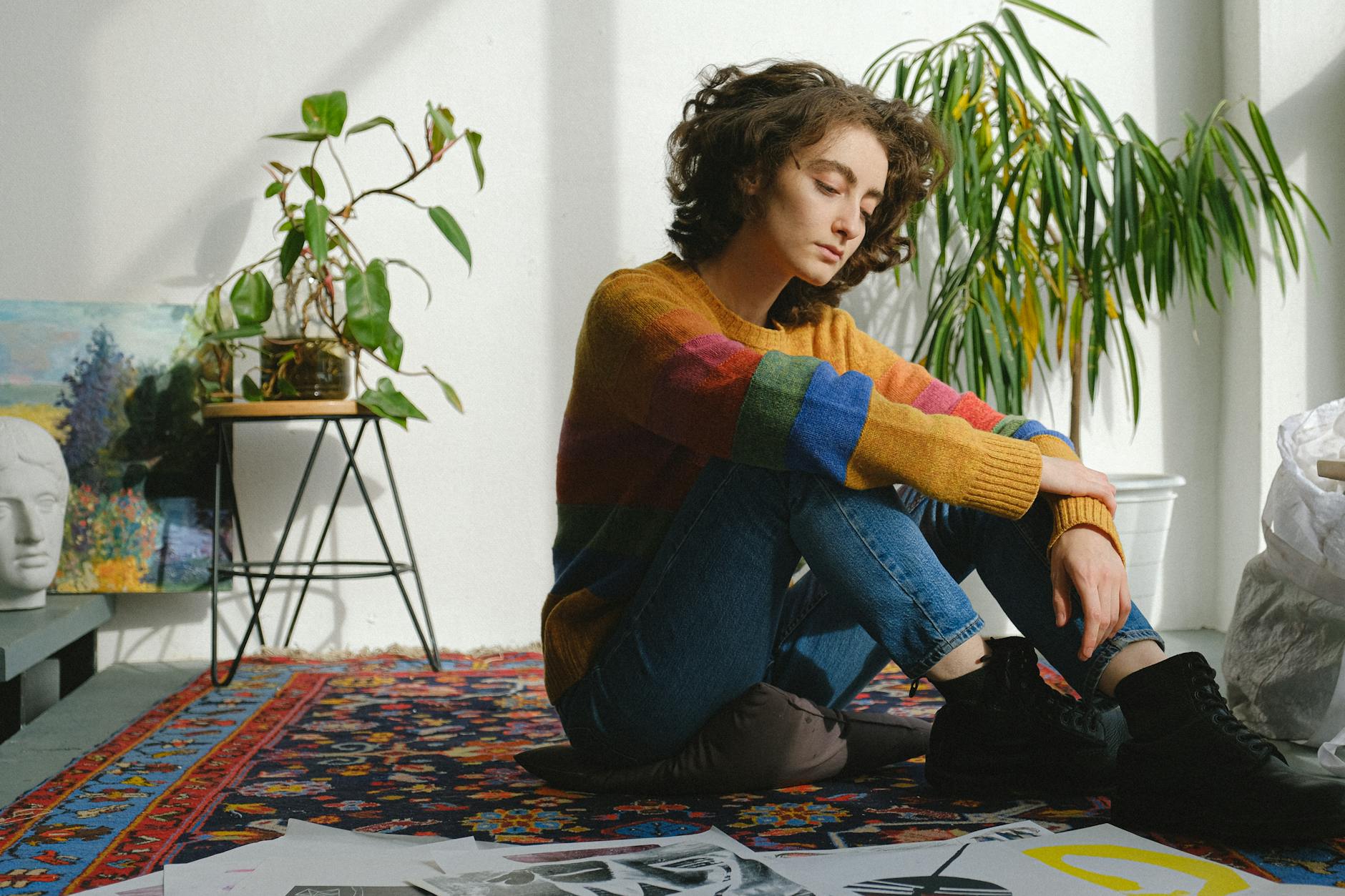 Lady sitting near paintings on floor in studio