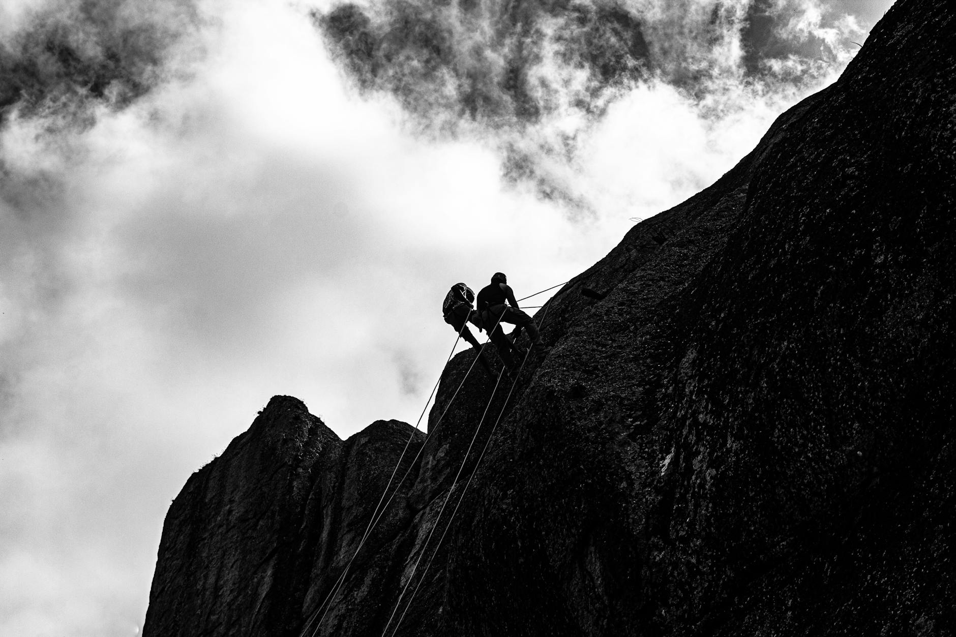 A black and white photo of a climber on a rock