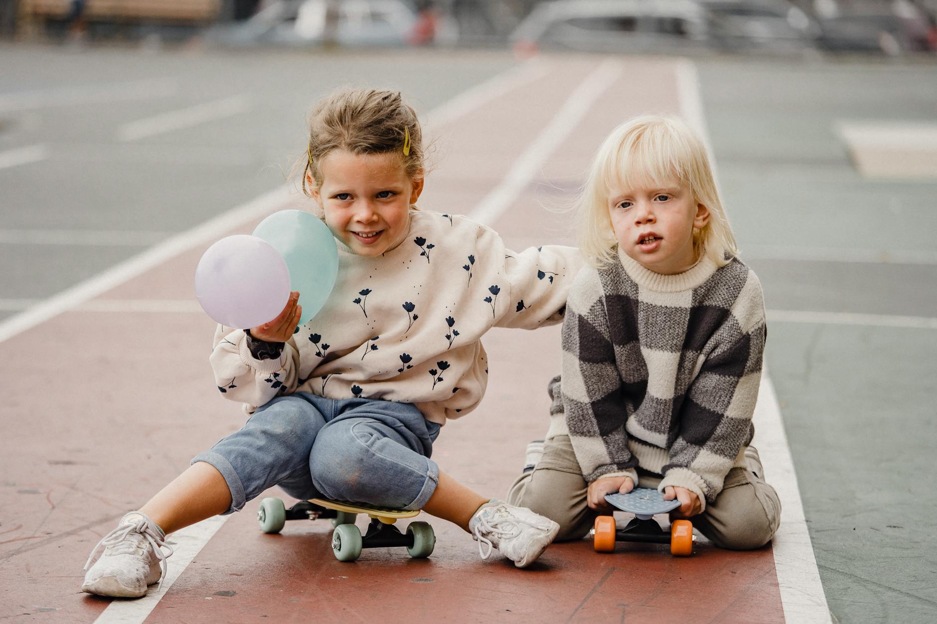 Children sitting on skateboards on street