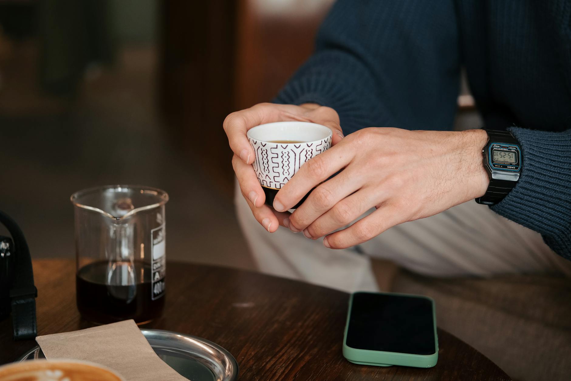 A person holding a cup of coffee and a phone