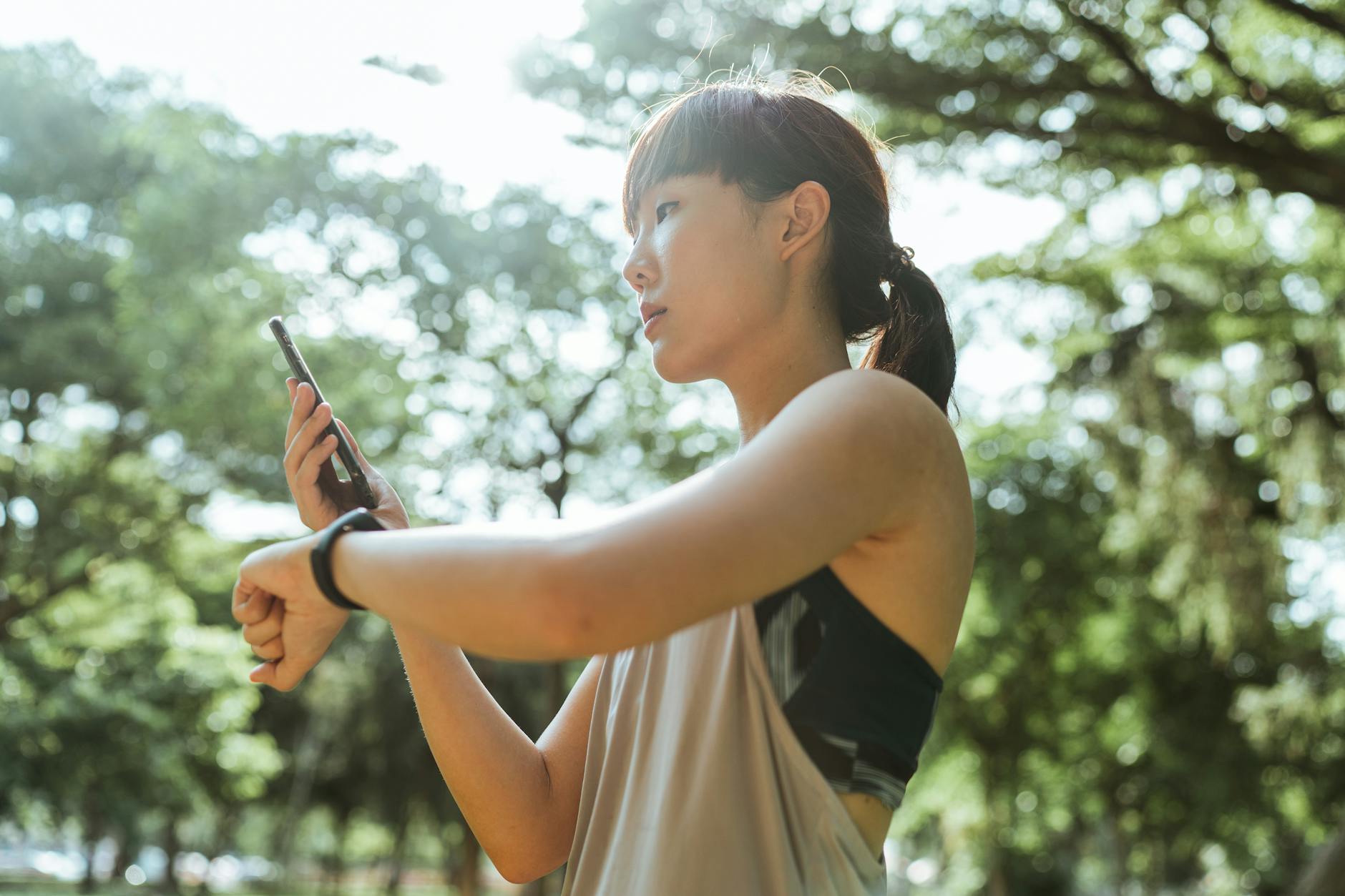 Young Asian woman using devices for fitness in park