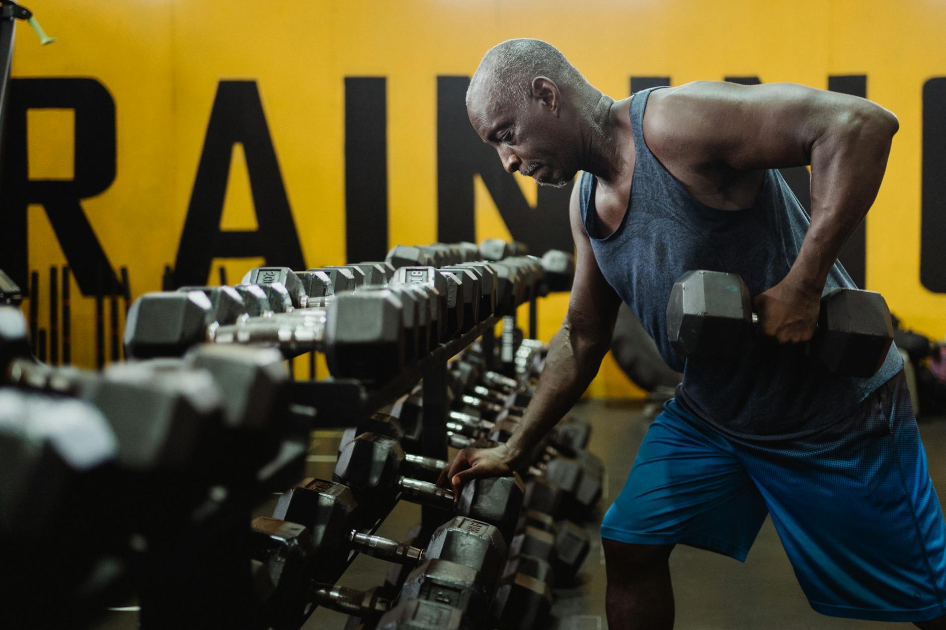 Man in Blue Tank Top Exercising With a Dumbbell