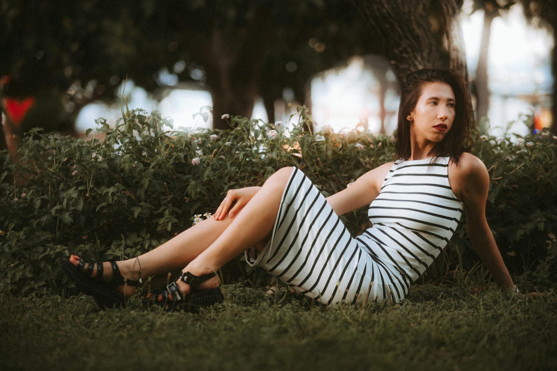 A woman in a striped dress sitting on the grass