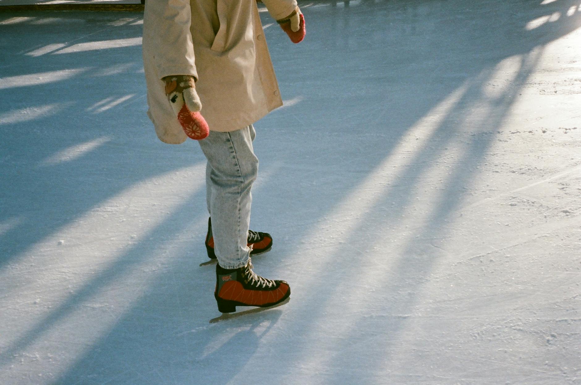 Faceless fit woman skating on ice rink in daylight