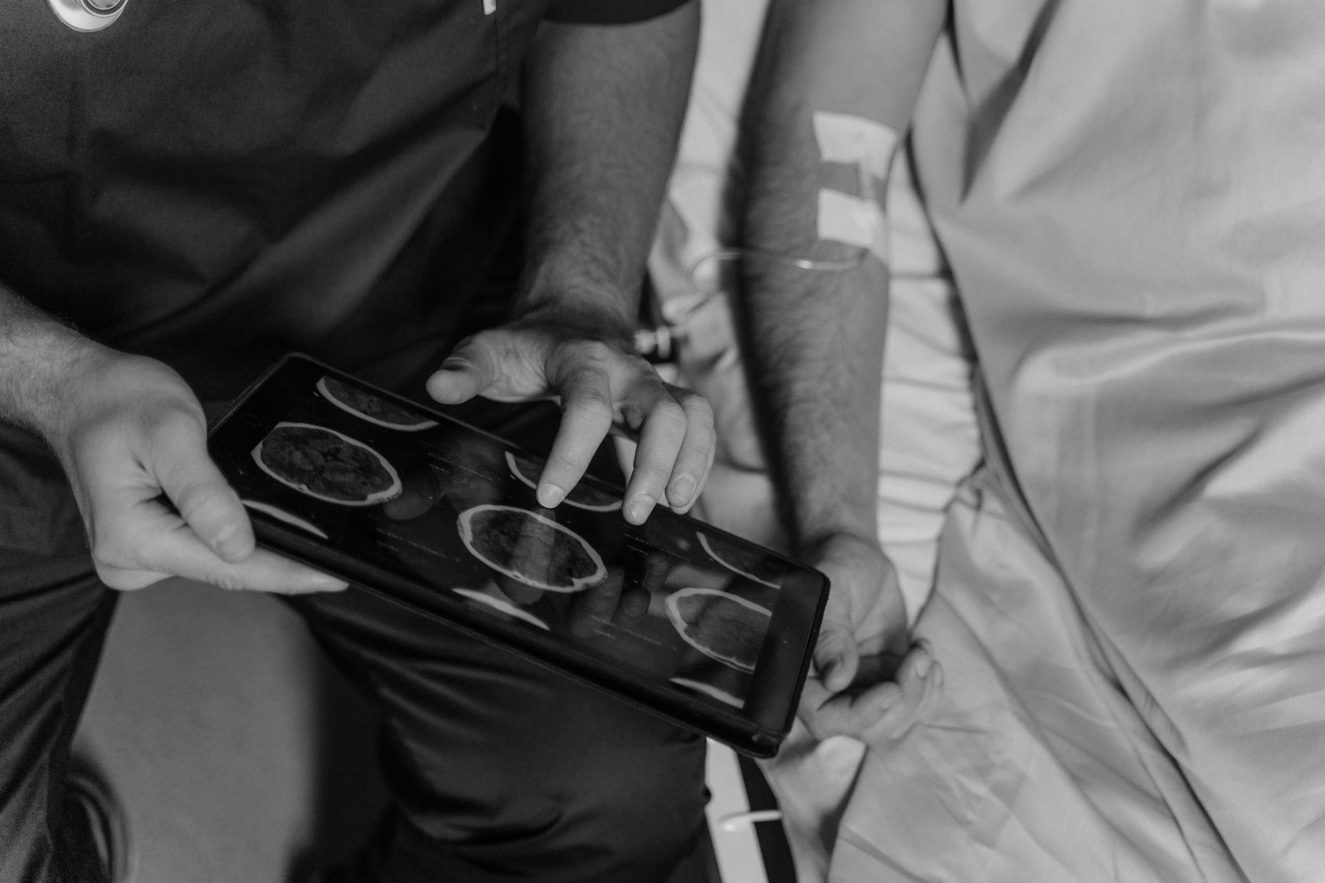 Grayscale Photo of a Doctor Using a Digital Tablet