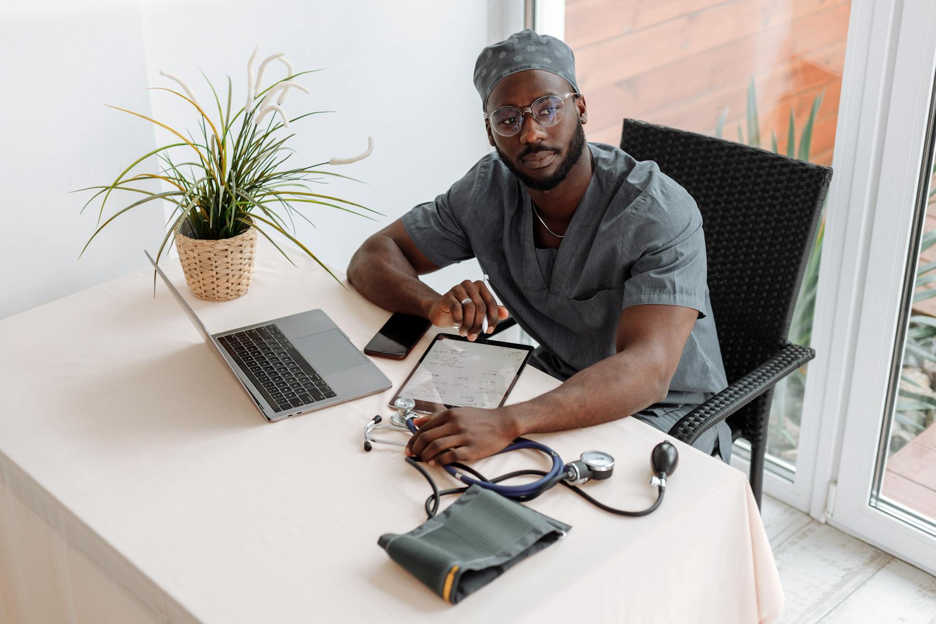 Man Sitting on a Chair infront of a Table with Laptop and Tablet