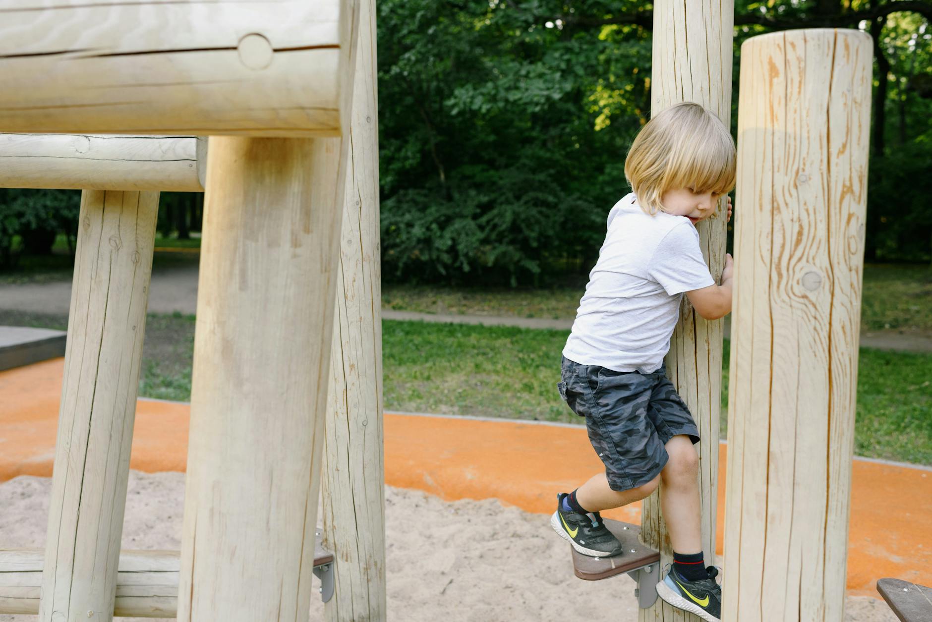 A Boy Playing on Playground's Wooden Equipment