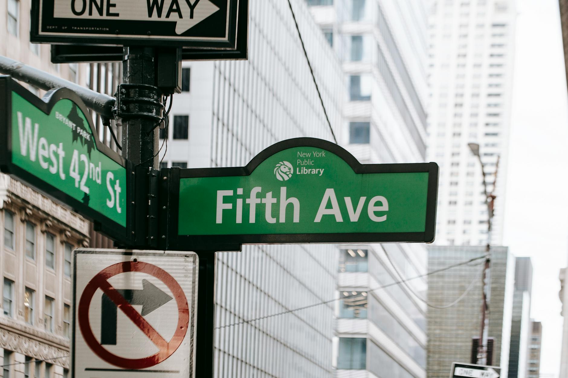 Metal post with direction indicator on avenue with high skyscrapers in New York