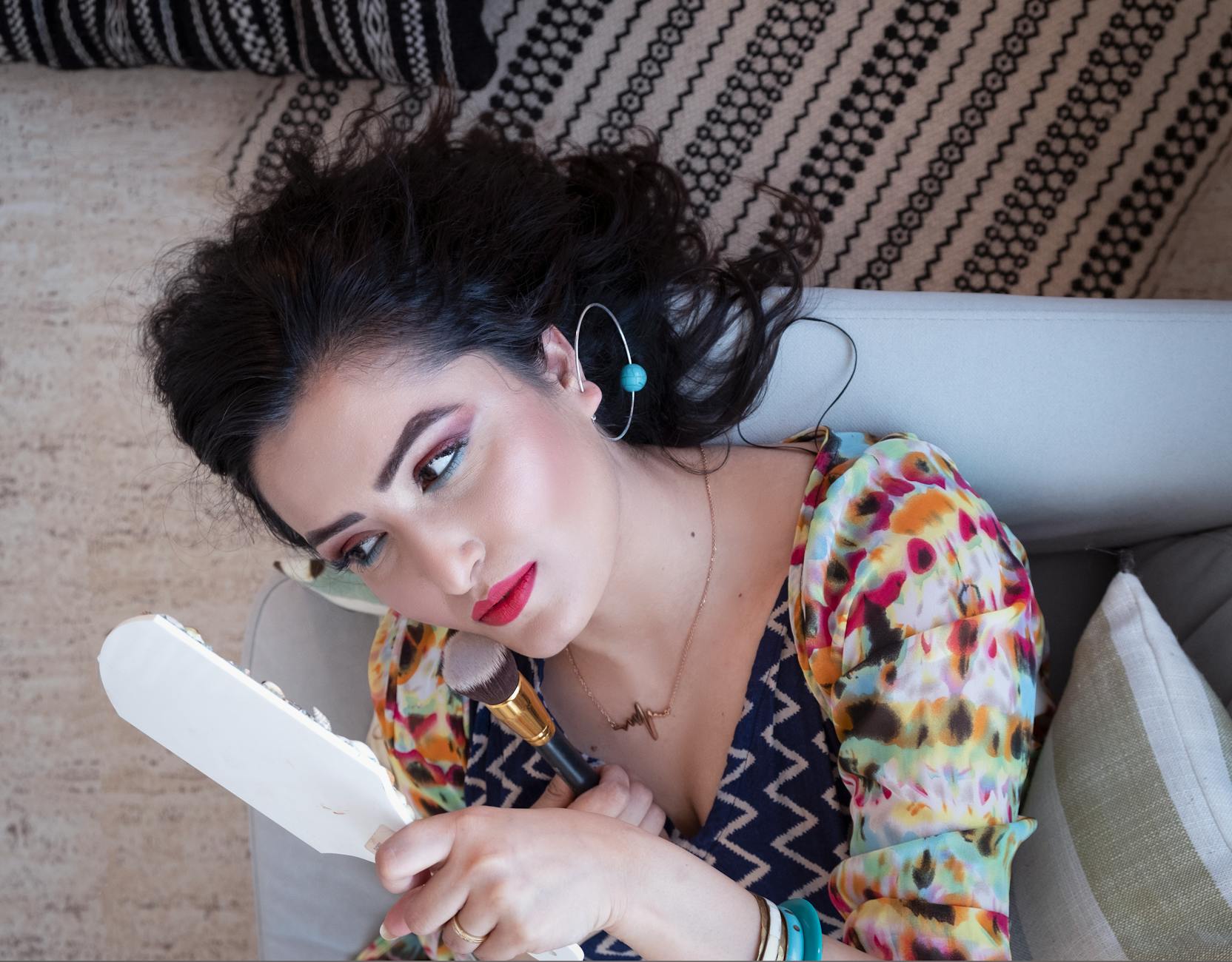 Woman Lying On Sofa Holding Mirror