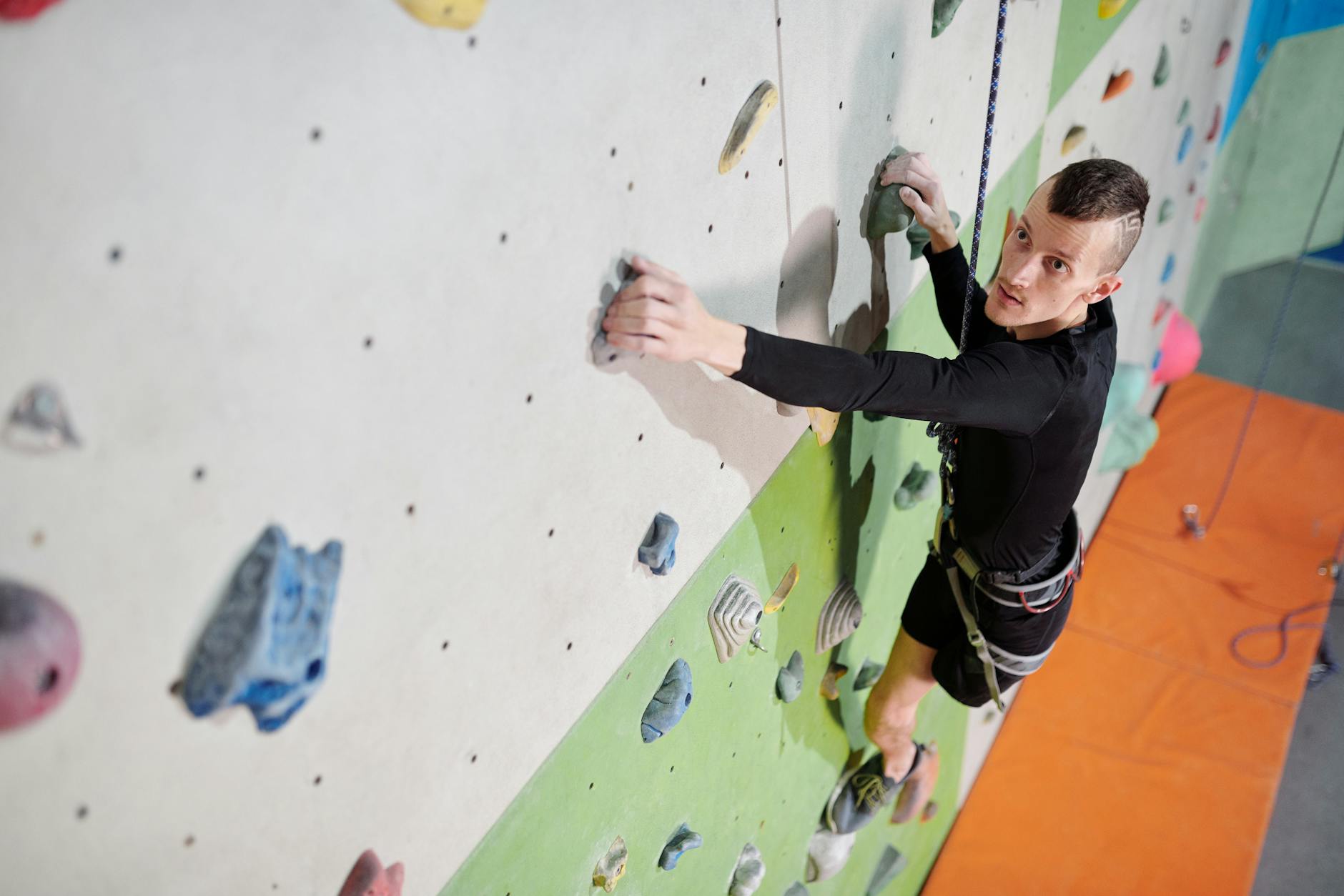 Man in Black Long Sleeve Shirt and Black Pants Climbing on Wall