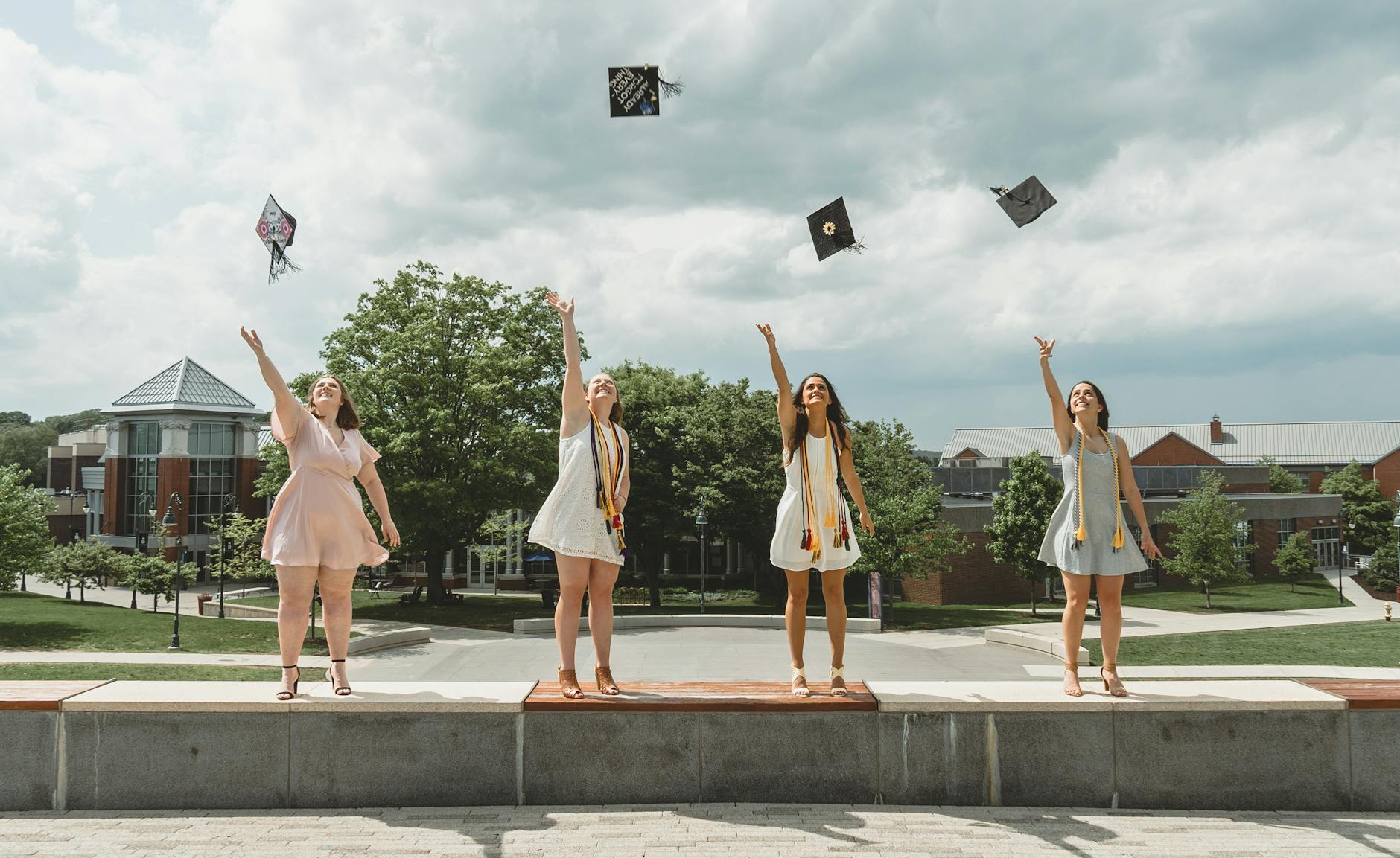 3 Women in White Dresses Standing on Gray Concrete Pavement