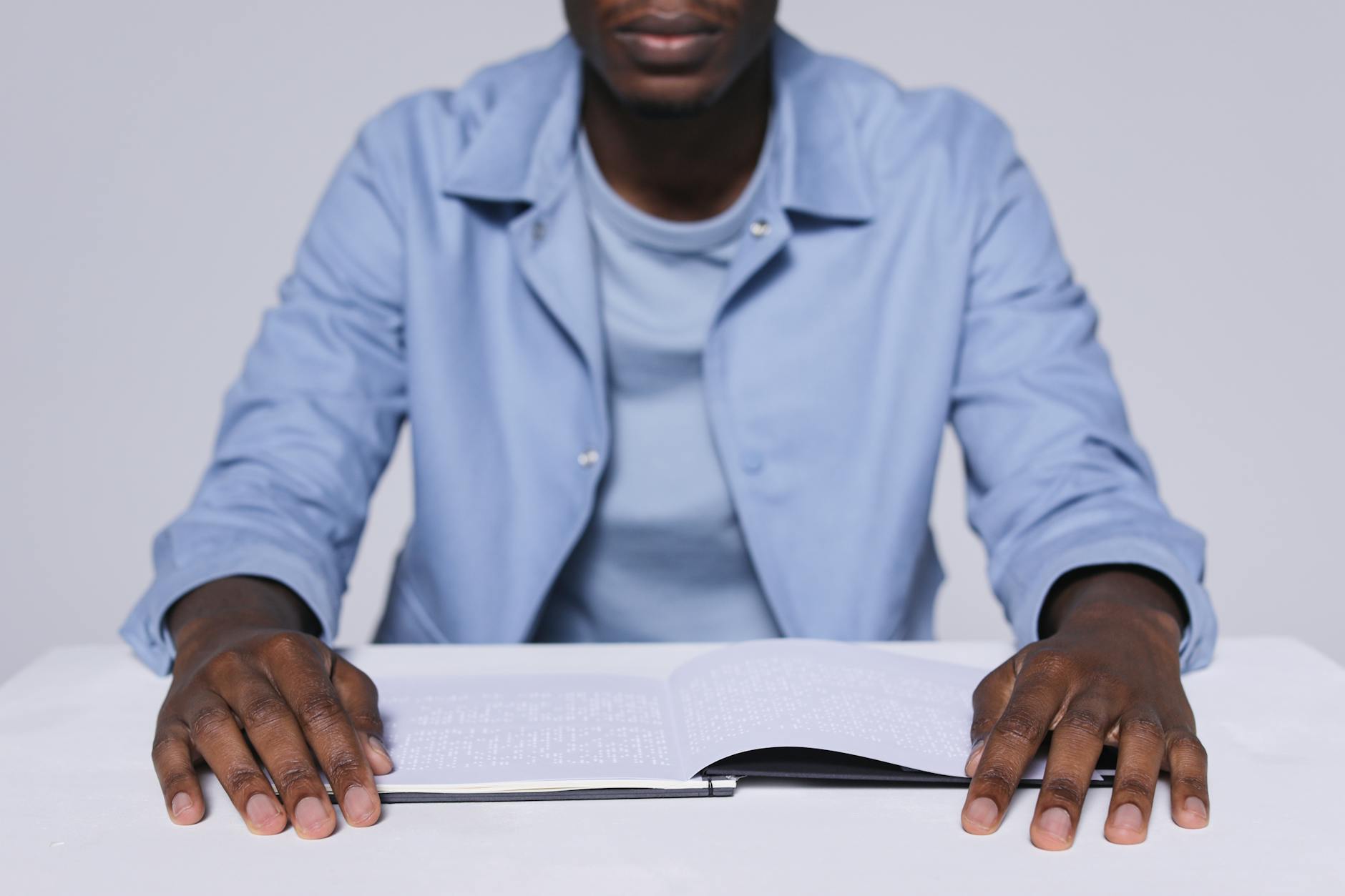 A Man in Blue Long Sleeves Reading a Braille