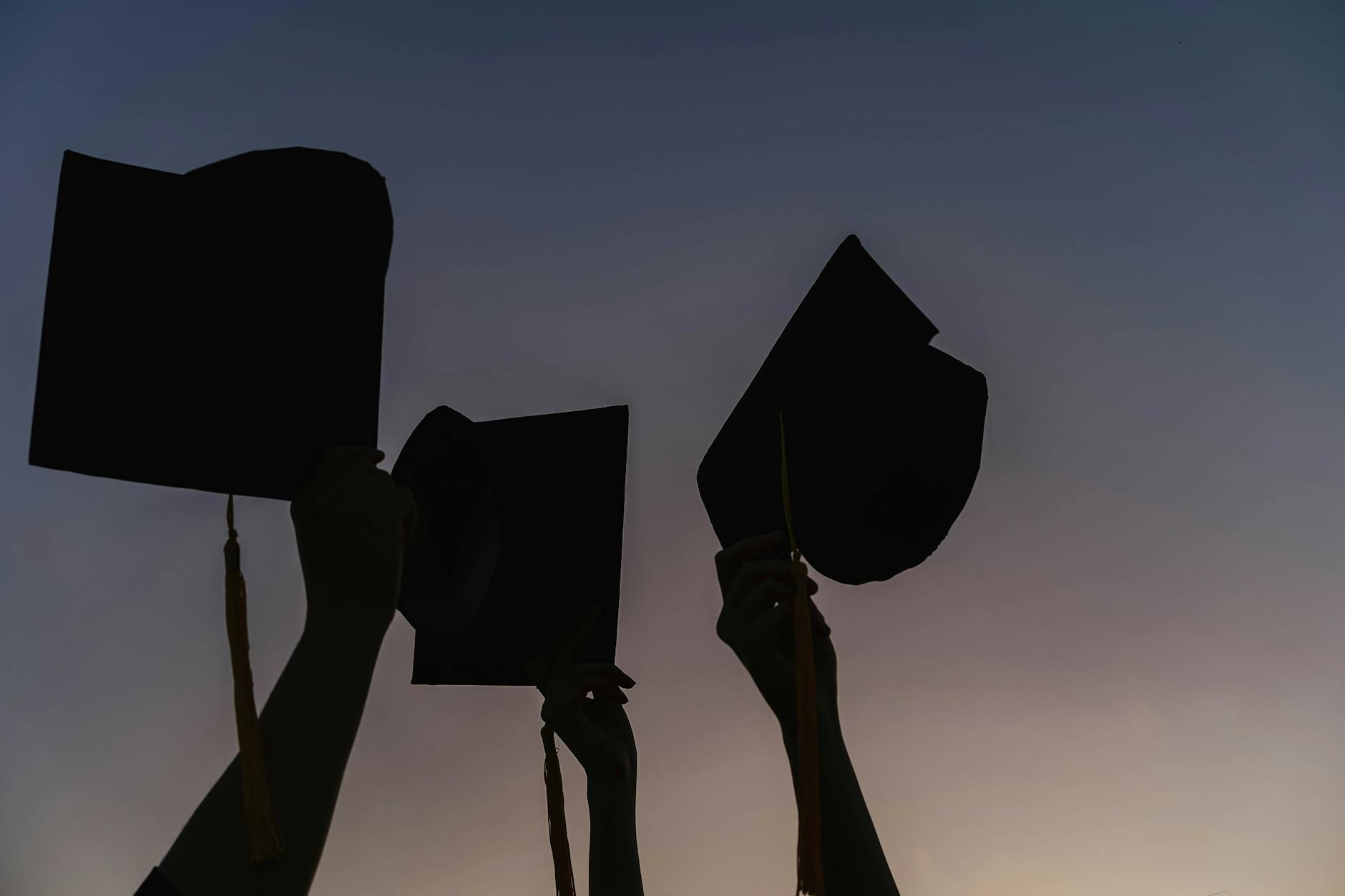 Silhouette of People Holding Graduation Caps