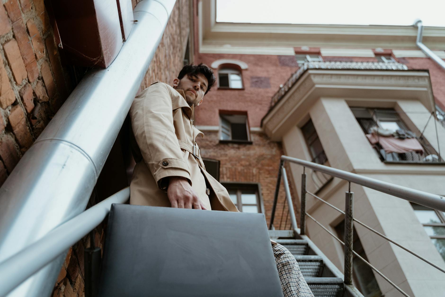 Low Angle Shot of a Man in Brown Coat Standing on a Building Stairs